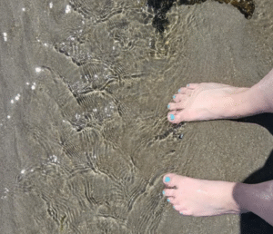 Bare feet with aqua nail polish toes in the water