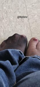 Black nylon pantyhose feet with red toe nail polish with jeans