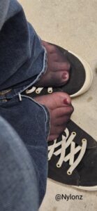 Black nylon pantyhose feet with red toe nail polish with jeans