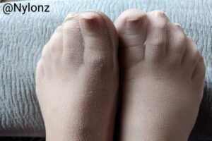 Nude nylon pantyhose feet with nude nail polish on toes